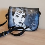 Borsa dipinta a mano,Haudry HANUL, elegante borsa a tracolla nera con la famosa immagine del film COLAZIONE DA TIFFANY un film del 1961 diretto da Blake Edwards, con Audrey Hepburn e George Peppard. DESCRIZIONE TECNICA Tasca con zip sul retro Chiusura con patta Tracolla in pelle e regolabile 2 scomparti Tasche interne Portapenne Tasche portacarte e portacellulare Dimensioni: 25cm x 18cm x 10cm (base x altezza x profondità) ATTENZIONE! ACQUISTANDO QUESTO PRODOTTO ACQUISTERETE LA SUA REPLICA E COME OGNI PRODOTTO DIPINTO A MANO SARA' MOLTO SIMILE MA MAI IDENTICA SEGNO DI AUTENTICITA' E UNICITA'. RICEVERETE LA BORSA ENTRO 30 GIORNI DAL PAGAMENTO PER PERMETTERCI DI ESEGUIRE TUTTE LE VARIE FASI CON METICOLOSITA' E PRECISIONE. GRAZIE PER AVER SCELTO HANUL